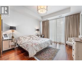 A bedroom with a large bed and a chandelier.
