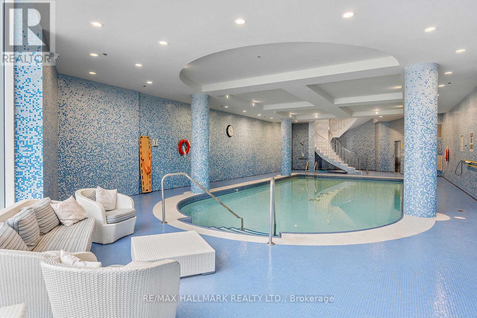 A large indoor swimming pool with a glass wall and a white sofa.