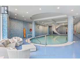 A large indoor swimming pool with a glass wall and a white sofa.
