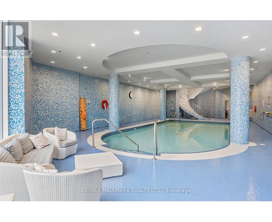 A large indoor swimming pool with a glass wall and a white sofa.