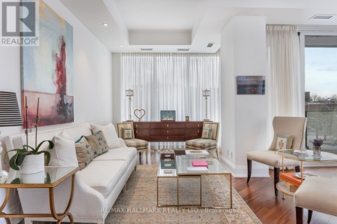 A living room with a white couch, a coffee table, and a painting on the wall.