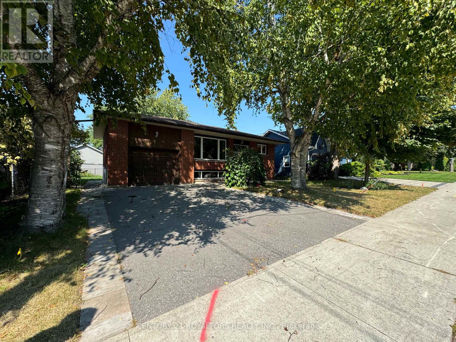 A house with a driveway and trees in front of it.