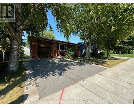 A house with a driveway and trees in front of it.
