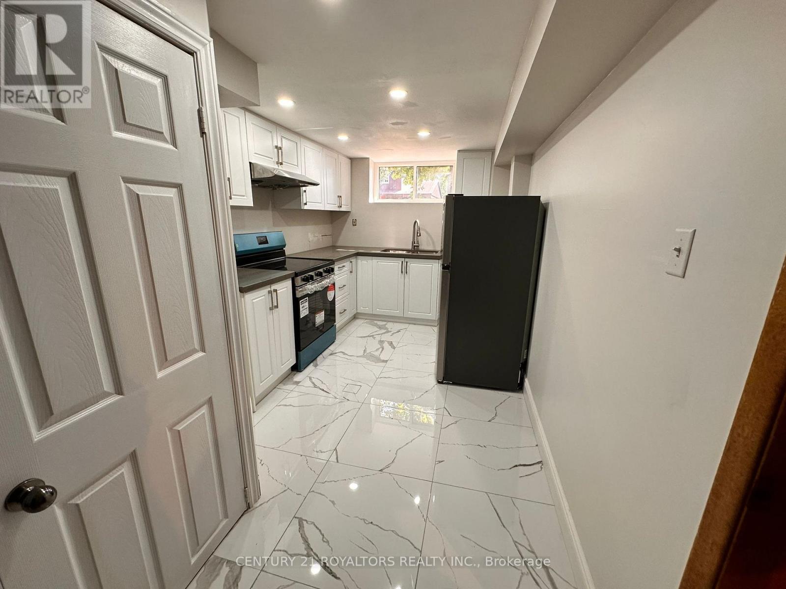 A kitchen with white cabinets and a black fridge.