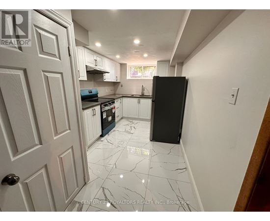 A kitchen with white cabinets and a black fridge.