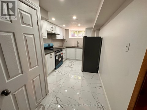 A kitchen with white cabinets and a black fridge.