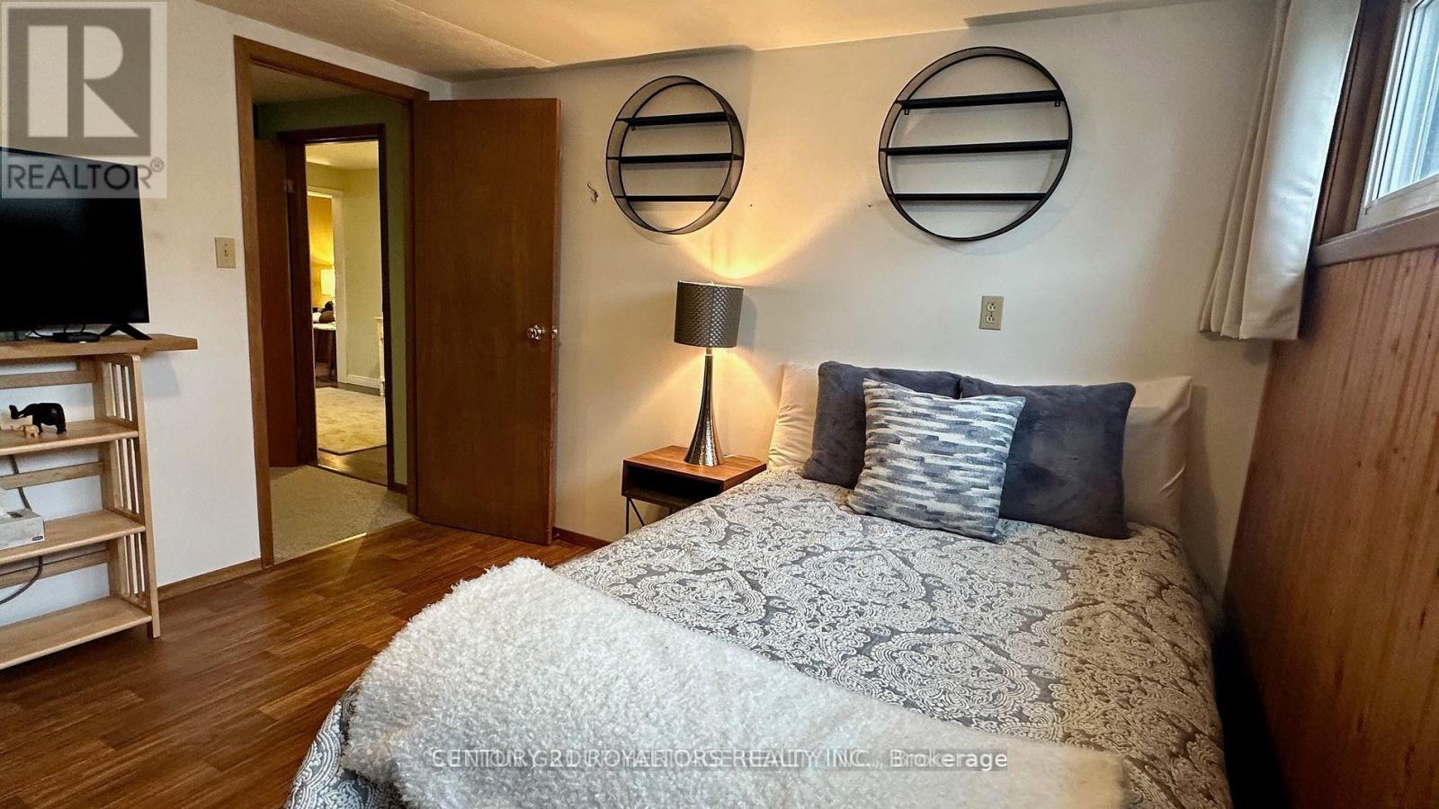 A bedroom with a bed, a nightstand with a lamp, and a TV on a stand.