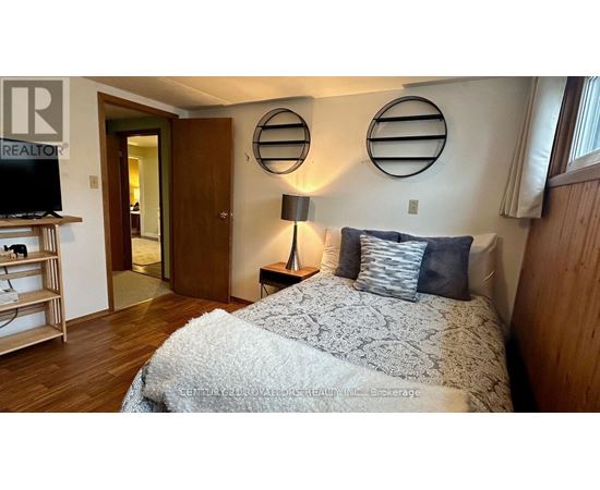 A bedroom with a bed, a nightstand with a lamp, and a TV on a stand.