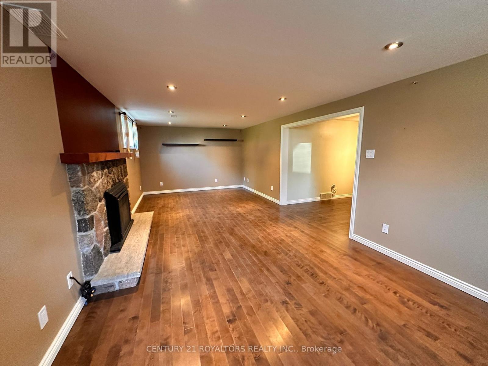 A spacious room with a fireplace and wooden flooring.