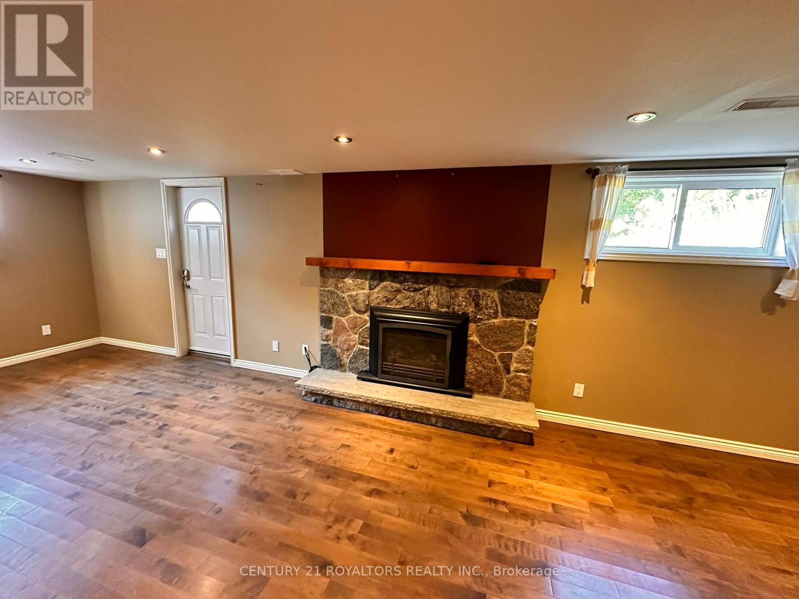 A living room with a stone fireplace and hardwood floors.