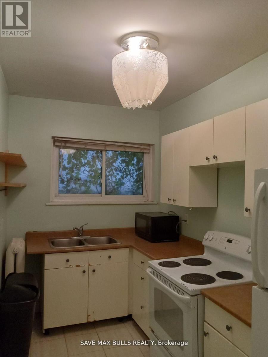 A kitchen with a stove, sink, and microwave.
