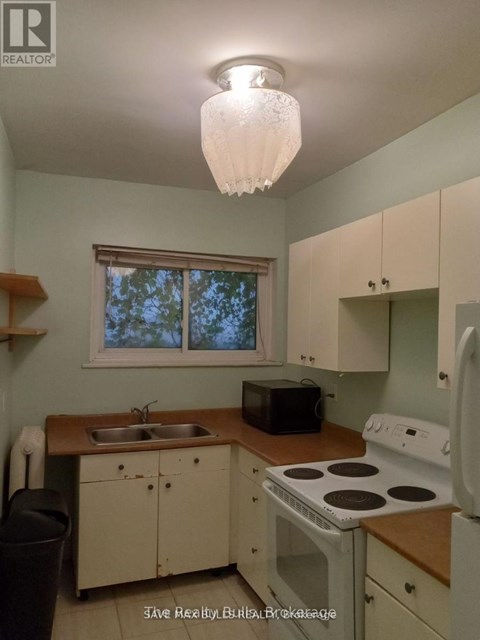 A kitchen with a stove, sink, and microwave.