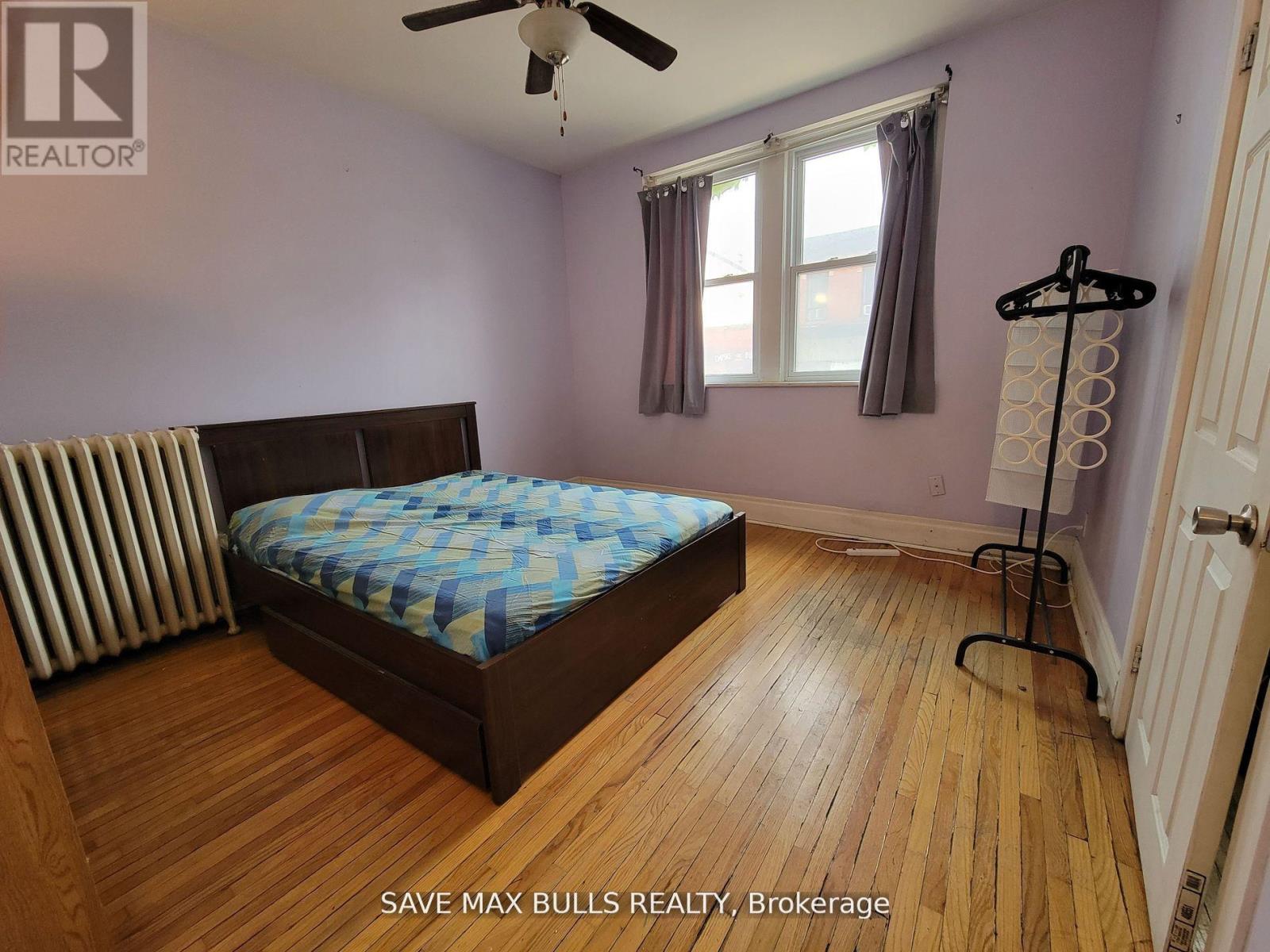 A bedroom with a bed, a ceiling fan, and a window.