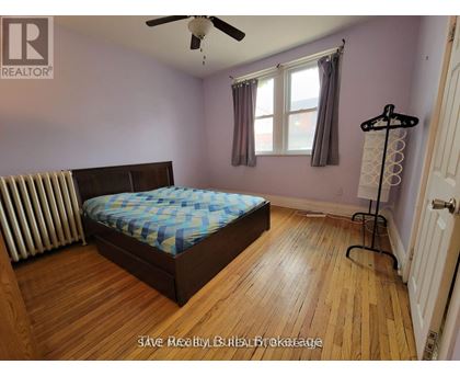 A bedroom with a bed, a ceiling fan, and a window.