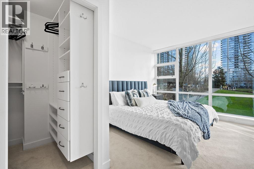A bedroom with a large bed and a view of a park through the window.