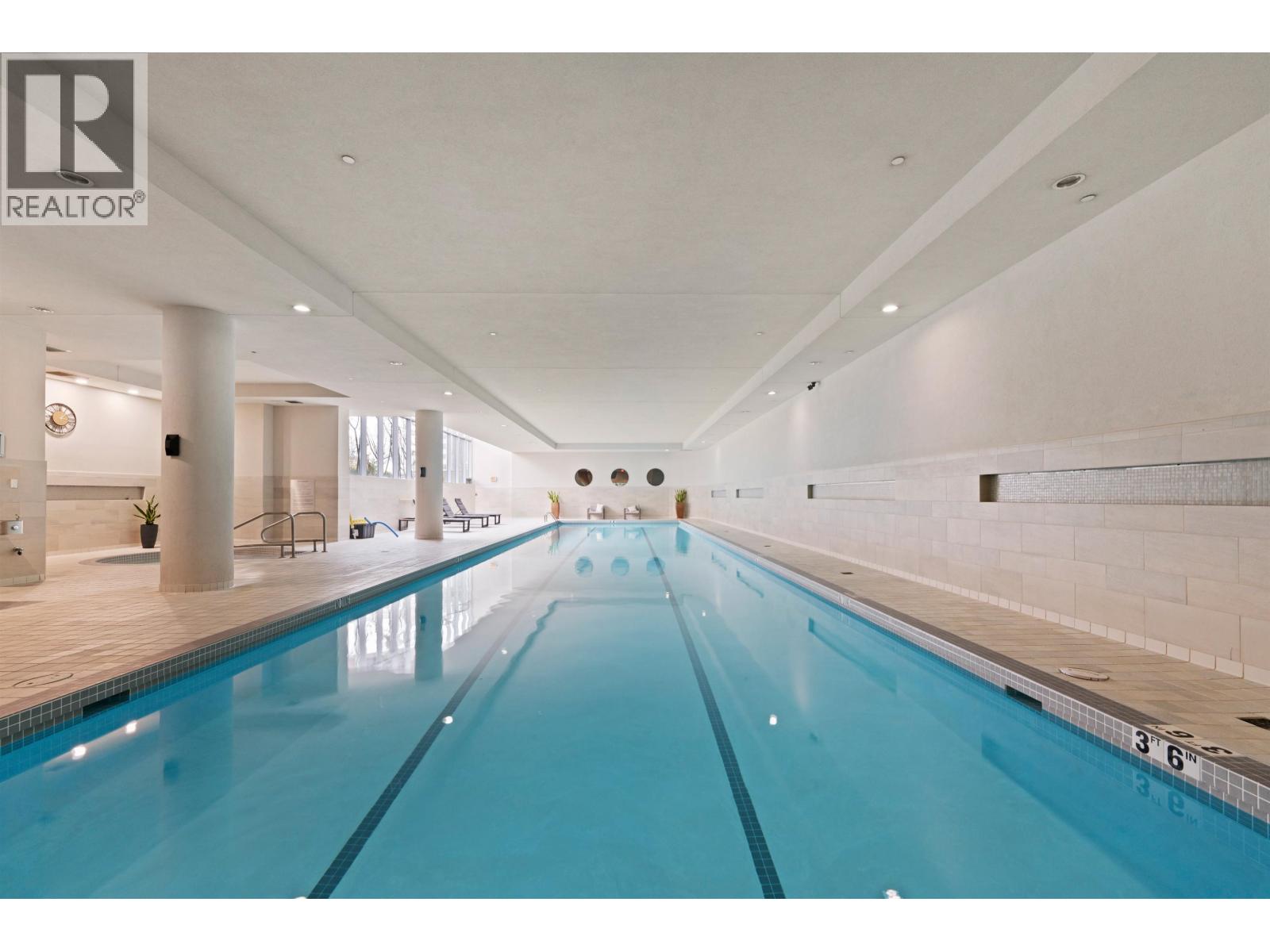 A large indoor swimming pool with a blue tinted water.