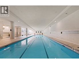 A large indoor swimming pool with a blue tinted water.