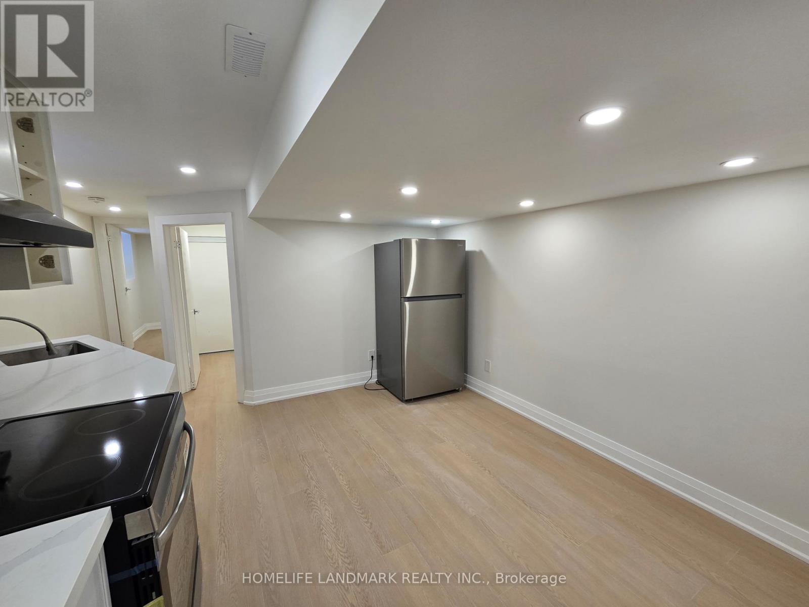 A kitchen with a stainless steel refrigerator and wooden flooring.