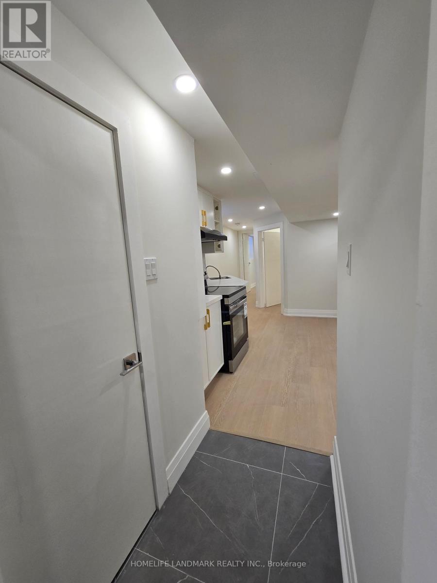A hallway with a white door and a kitchen area in the background.