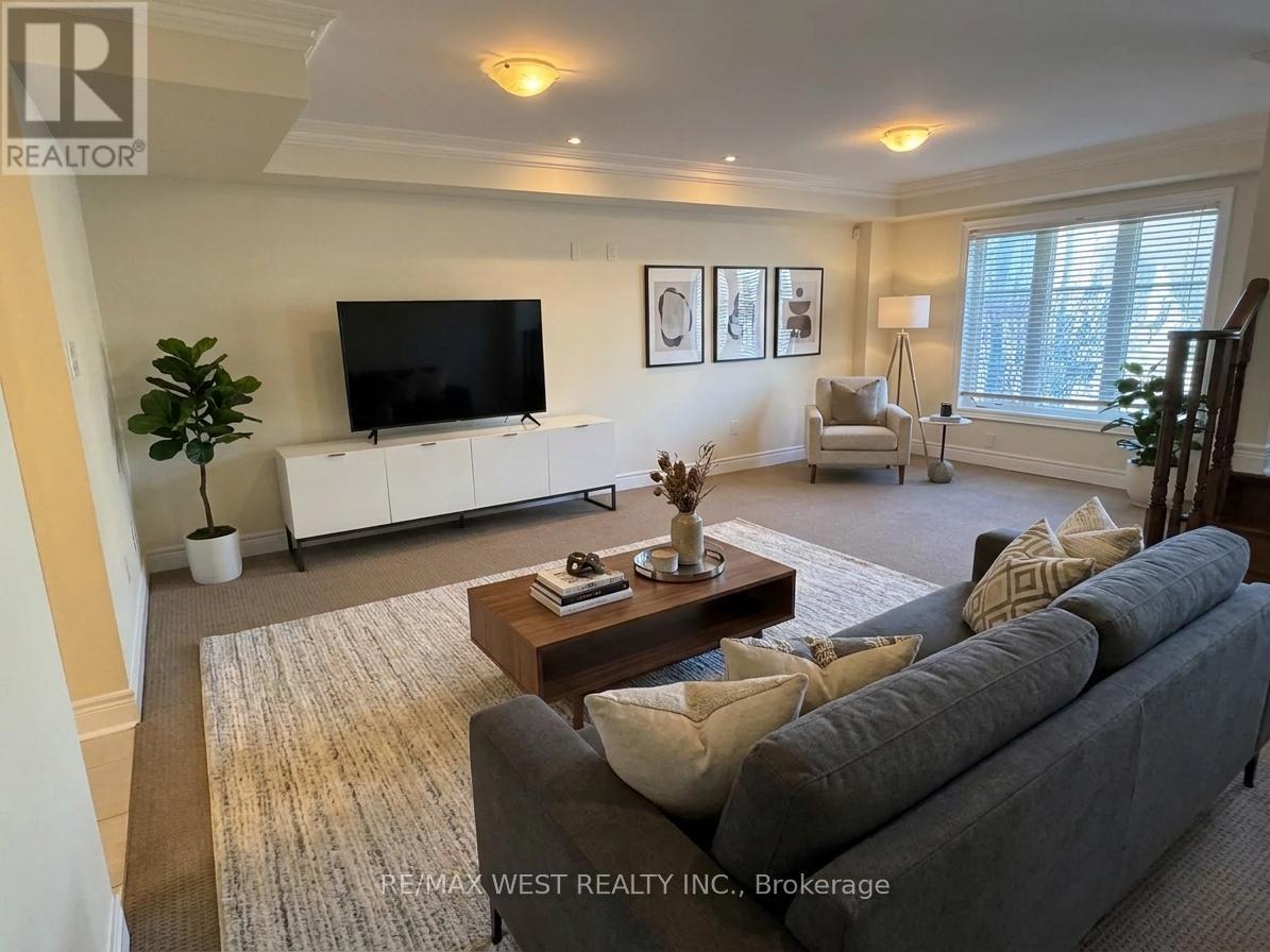 A living room with a grey couch, a coffee table, a flat screen TV, and a plant.