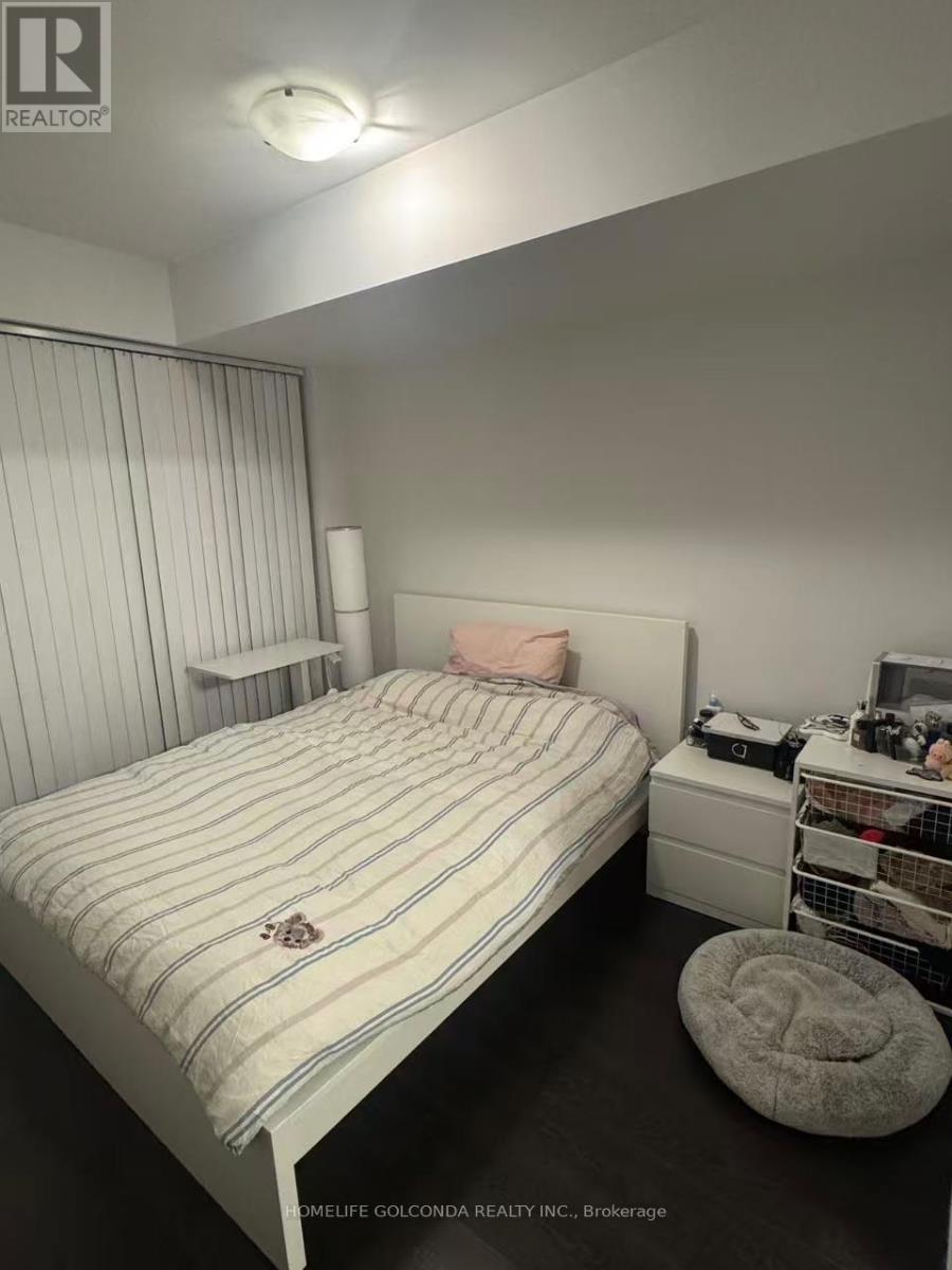 A bedroom with a bed, a nightstand, and a shelf with various items.