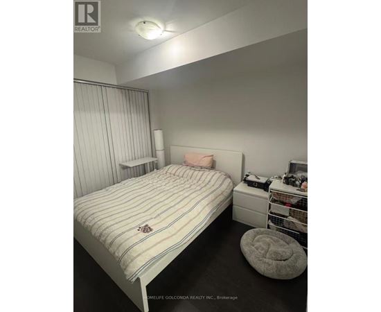 A bedroom with a bed, a nightstand, and a shelf with various items.