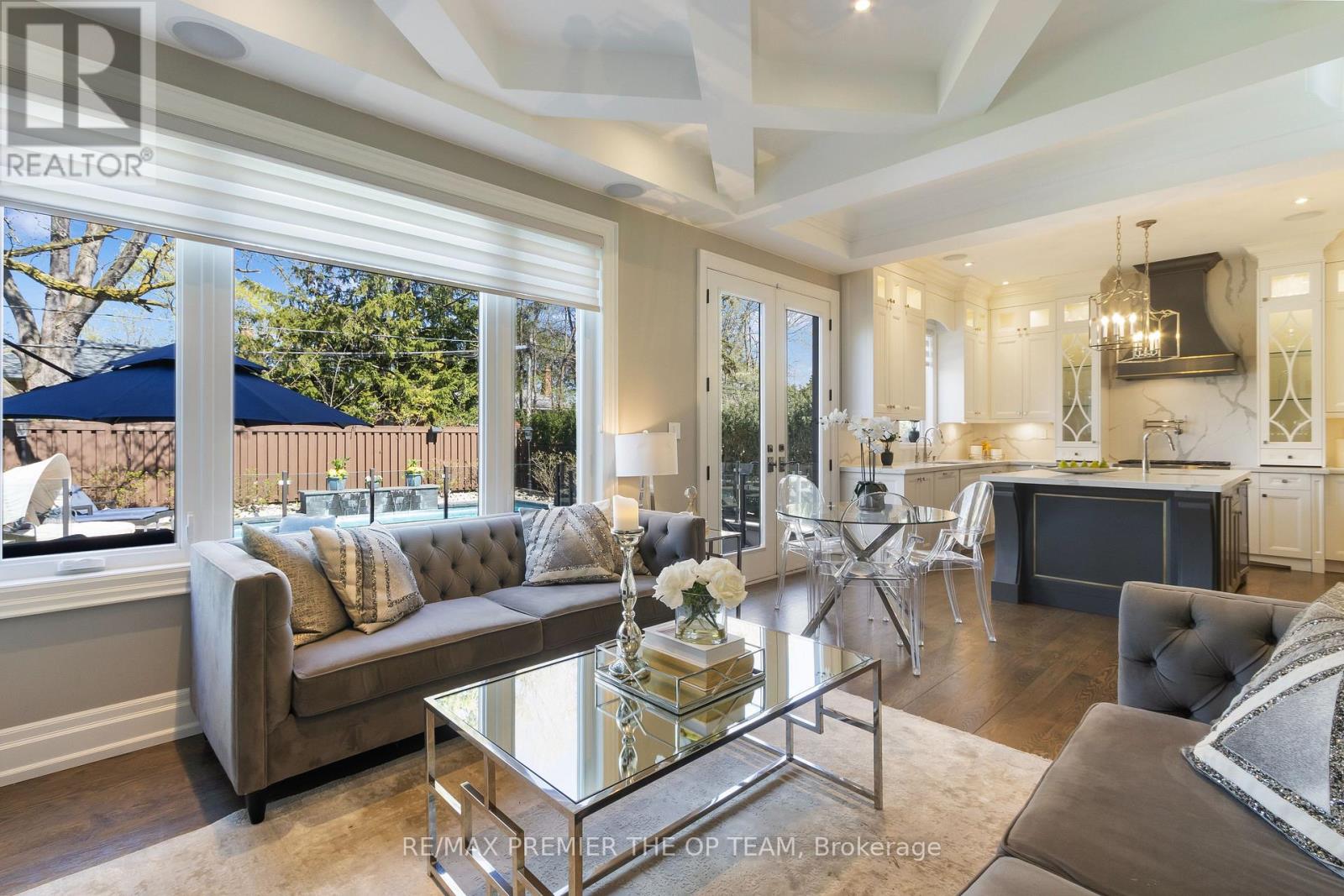 A well-lit, spacious living room with a grey sofa and a glass coffee table.