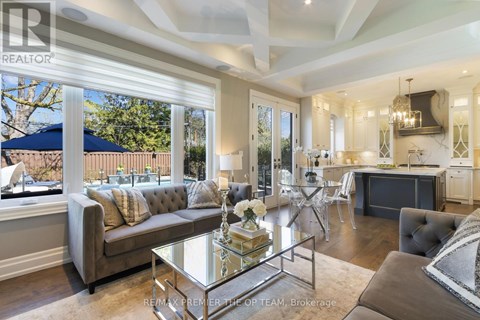 A well-lit, spacious living room with a grey sofa and a glass coffee table.