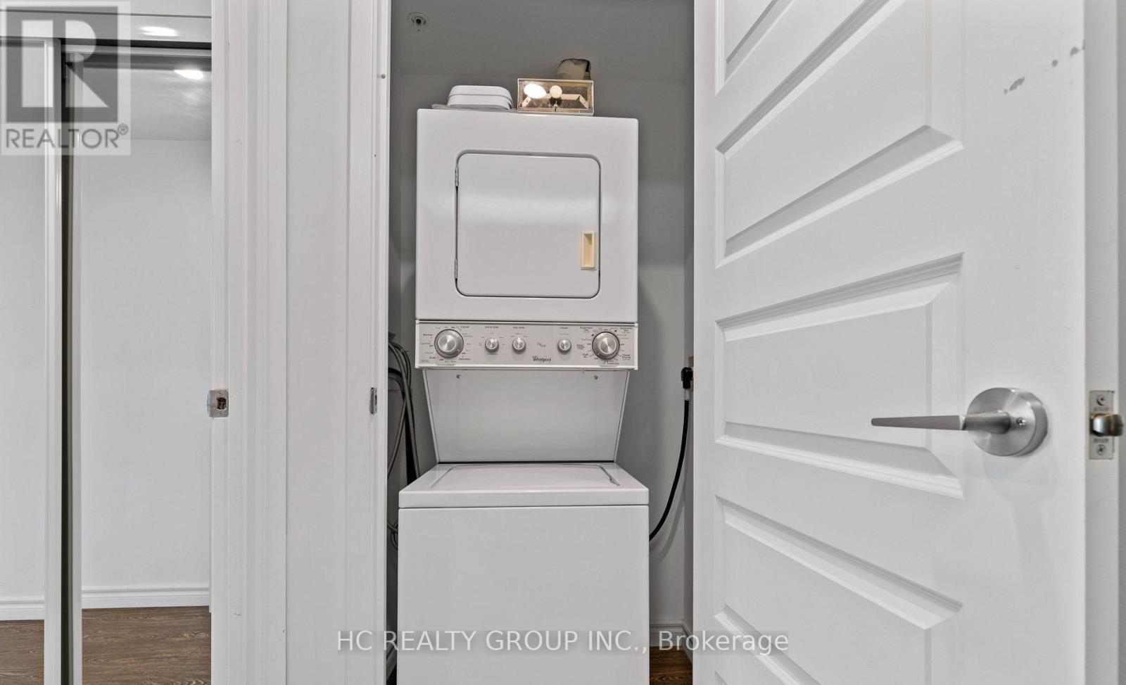 A white washing machine is in a small space between a door and a wall.