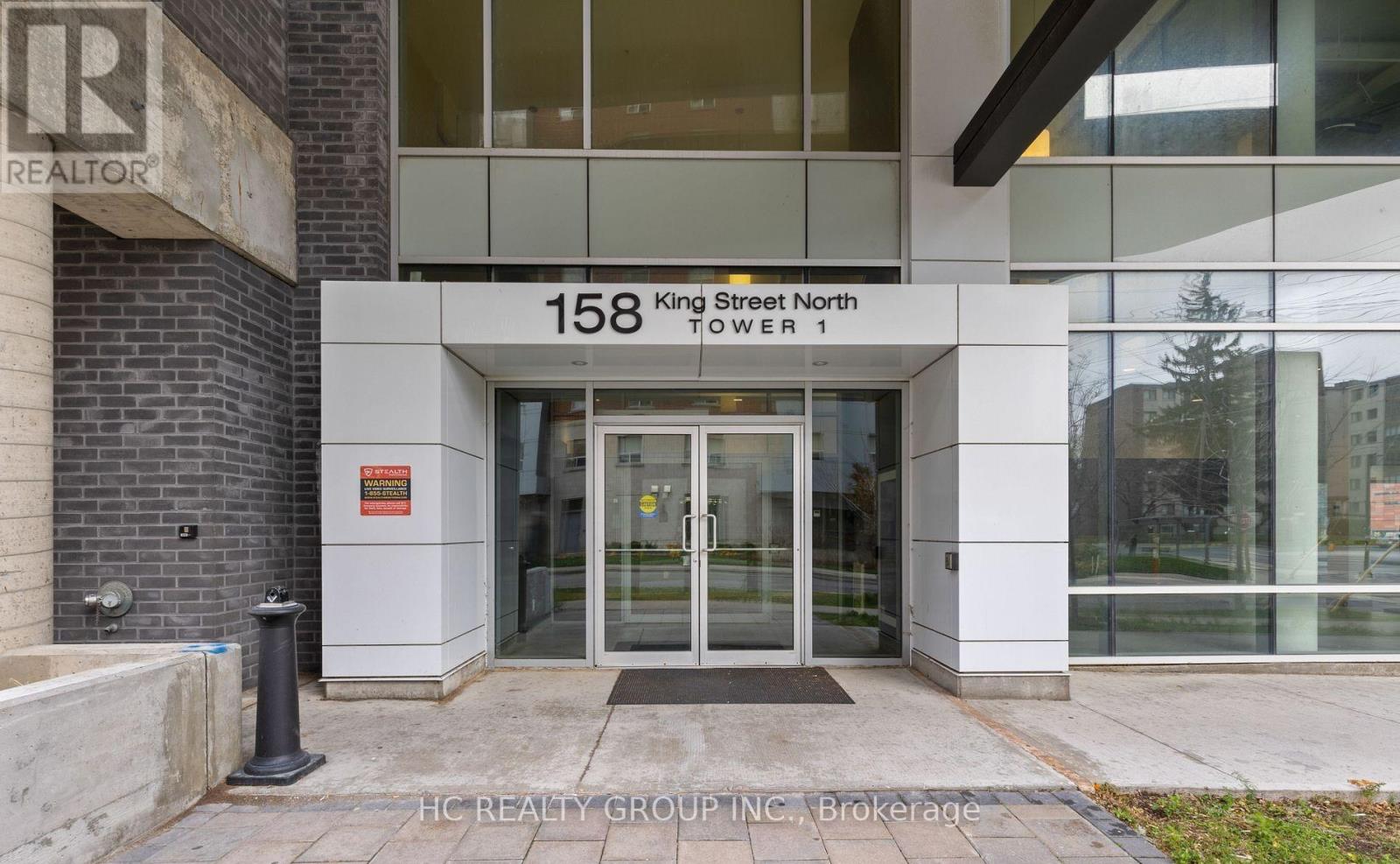 The front of a building with the sign "158 King Street North Tower 1" and a glass door entrance.
