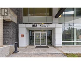 The front of a building with the sign "158 King Street North Tower 1" and a glass door entrance.