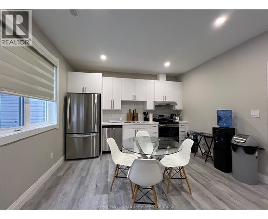 A kitchen with a refrigerator, dining table, and chairs.
