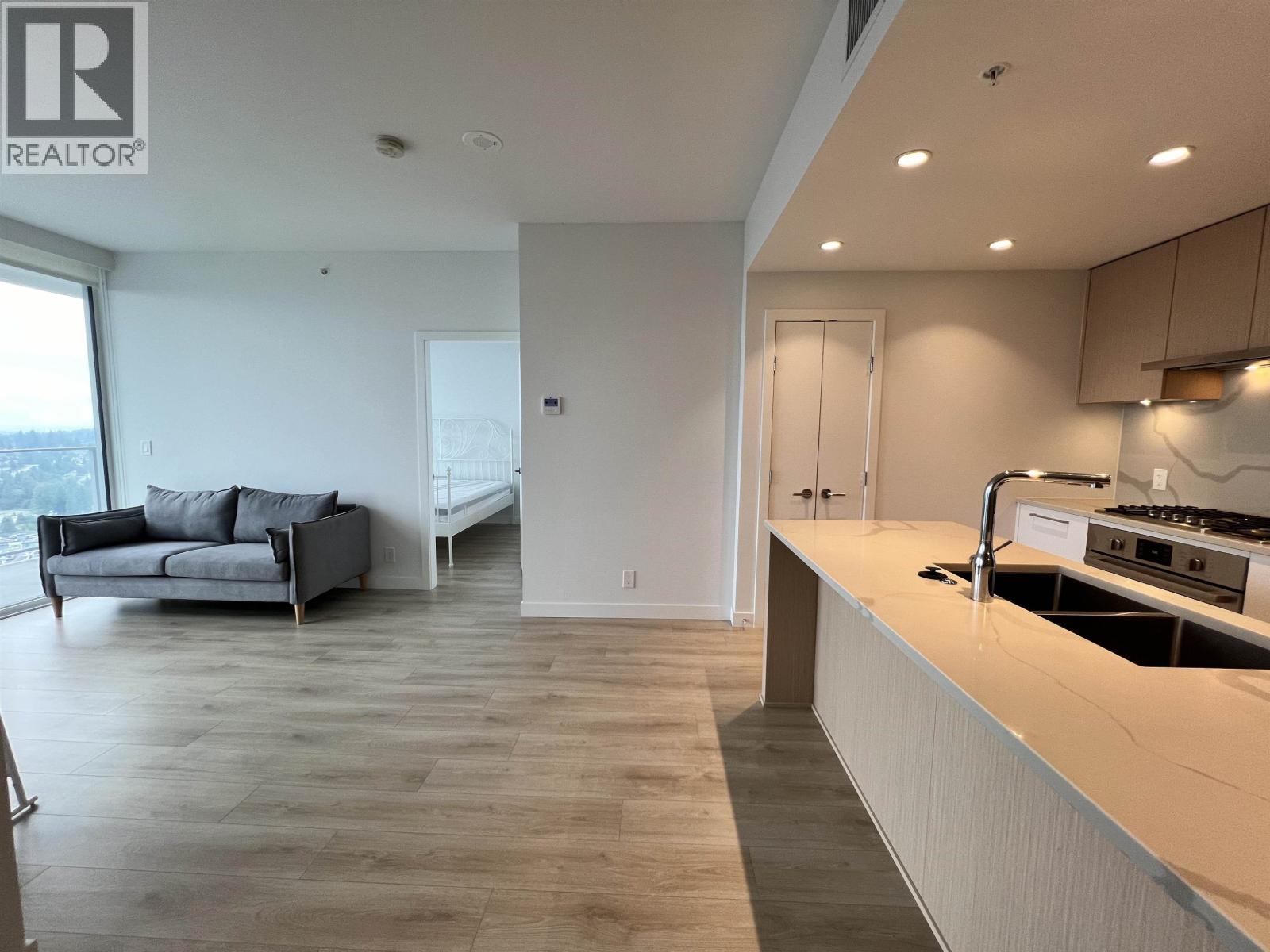 A modern kitchen with a large island and a living area with a couch and a window.