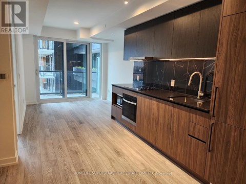 A modern kitchen with wooden cabinets and a black countertop.