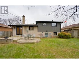 A house with a grey exterior and a patio with chairs.