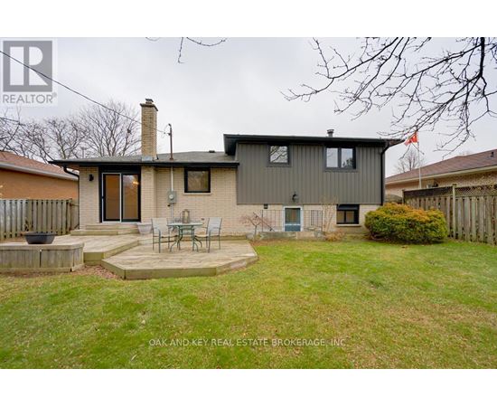 A house with a grey exterior and a patio with chairs.
