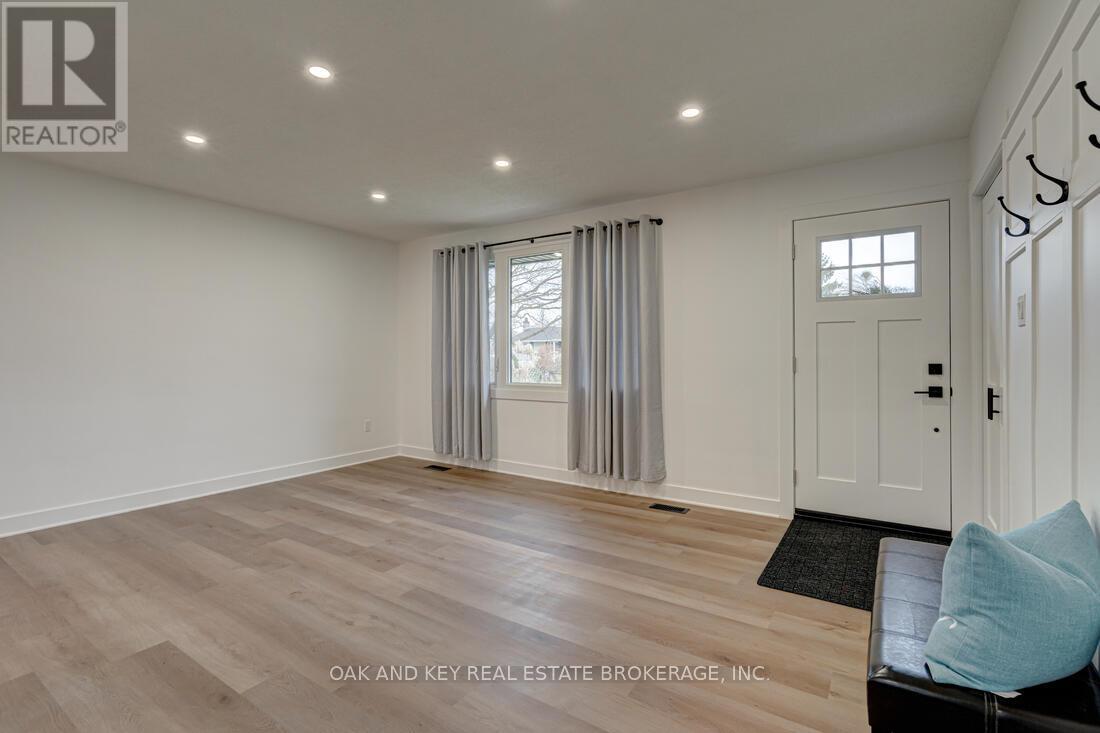 A spacious room with a door, a window with curtains, and a black mat on the floor.