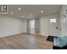 A spacious room with a door, a window with curtains, and a black mat on the floor.