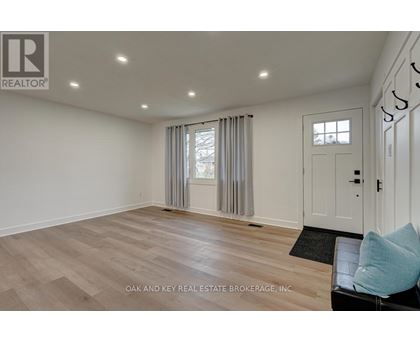 A spacious room with a door, a window with curtains, and a black mat on the floor.