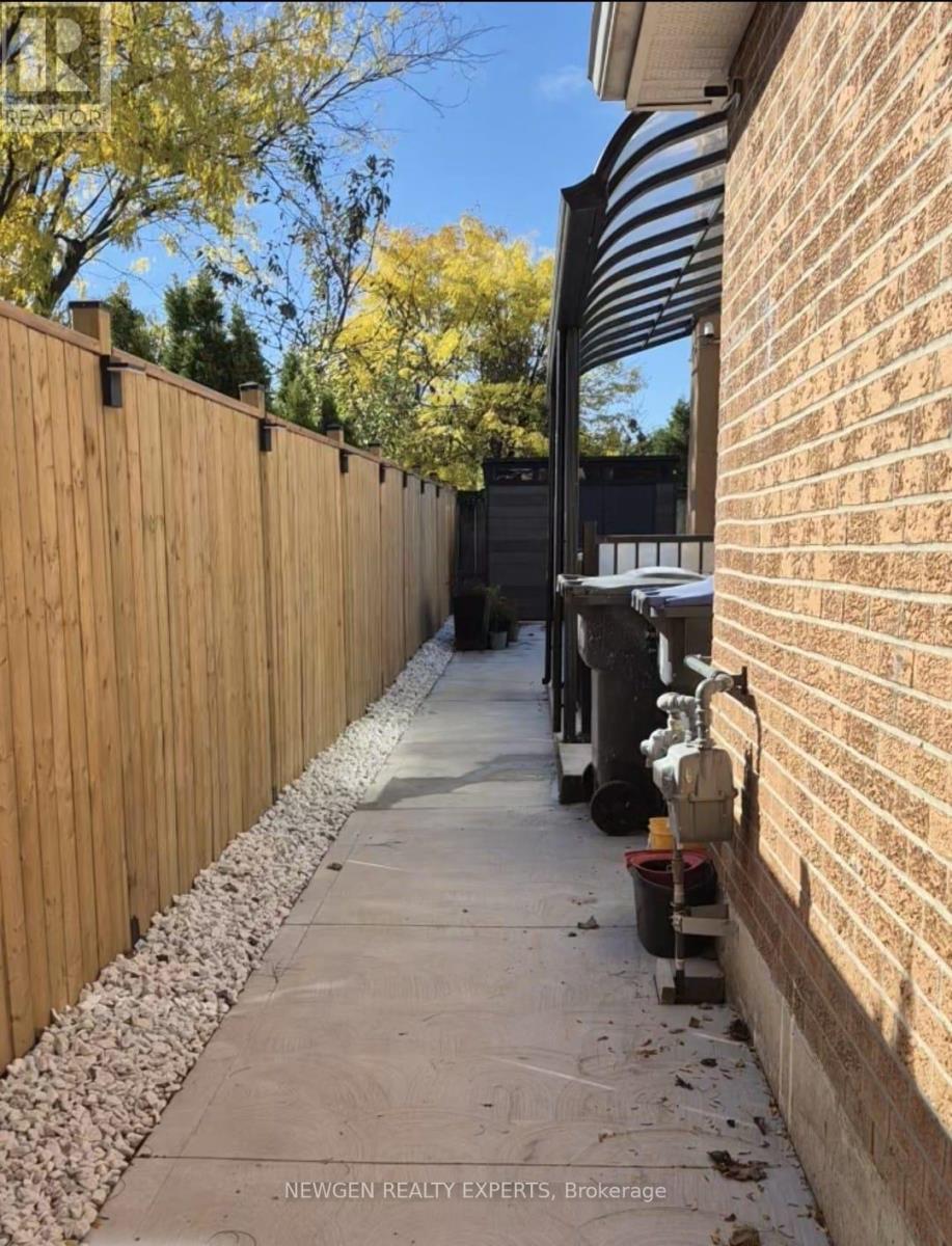 A wooden fence runs along the side of a brick building.