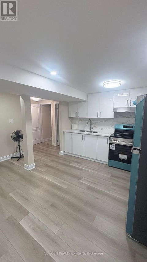 A kitchen with white cabinets and a wooden floor.