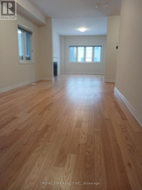 A spacious room with wooden flooring and white walls.