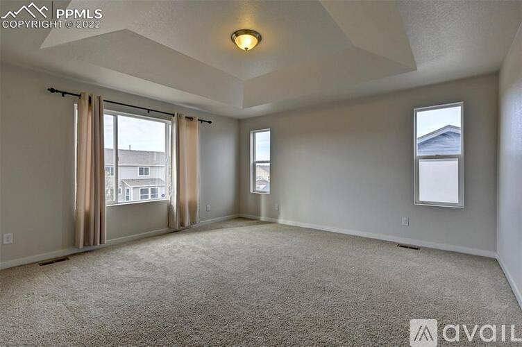 A spacious room with a carpeted floor and a window with curtains.