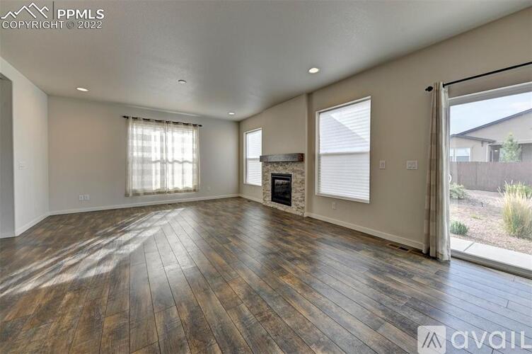 A spacious living room with wooden flooring and a fireplace.