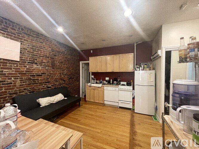 A kitchen with a black couch and wooden floors.
