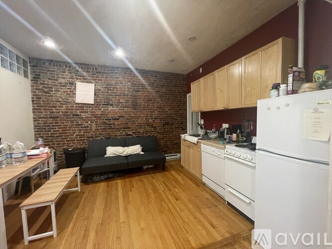 A kitchen with a black couch and wooden floors.