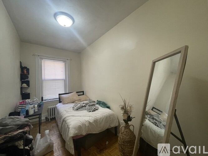 A bedroom with a bed, a mirror, and a window.