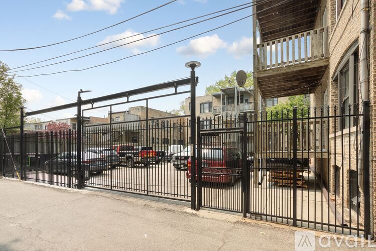 A black metal fence with a gate in front of a building with a balcony.