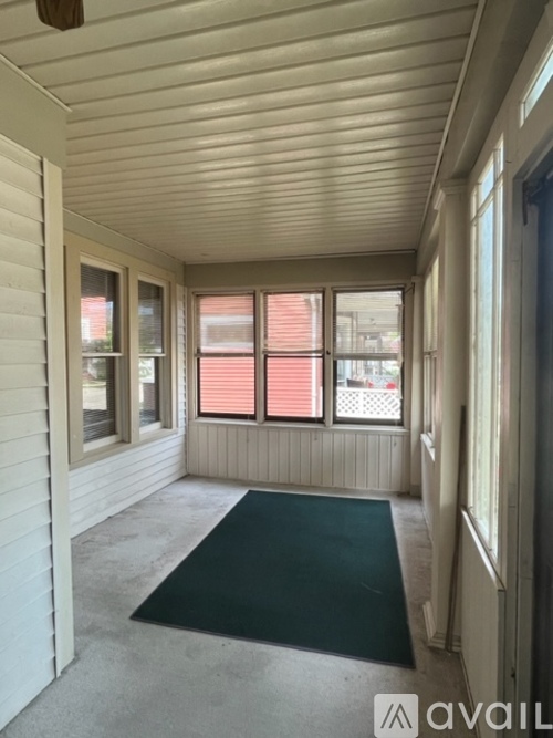 A room with a green rug and a window with red blinds.