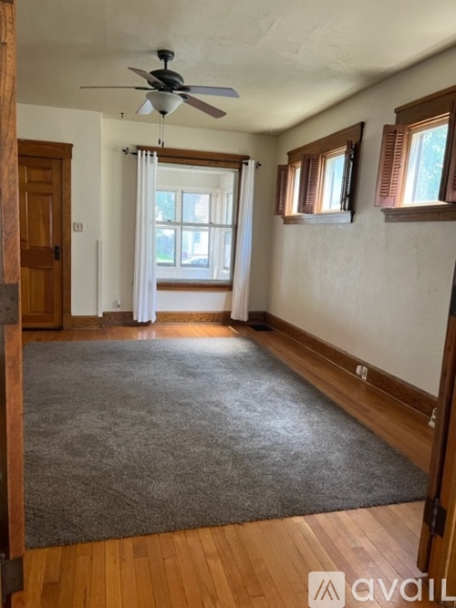 A room with a ceiling fan and a rug on the floor.